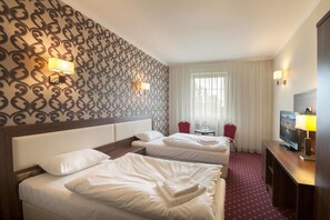 Une chambre d’hôtel avec deux lits, une télévision, un bureau et une fenêtre avec des rideaux.