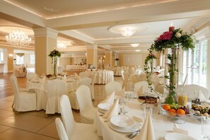 Un salón de banquetes con mesas redondas, manteles blancos y sillas.