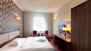 A hotel room with a bed, two chairs, a desk, a TV, and a wardrobe. - Dworek Eureka (Czechowice-Dziedzice)