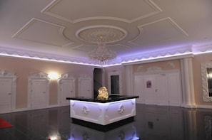 Quarto amplo com ilha central, um candelabro e portas brancas ricamente decoradas.