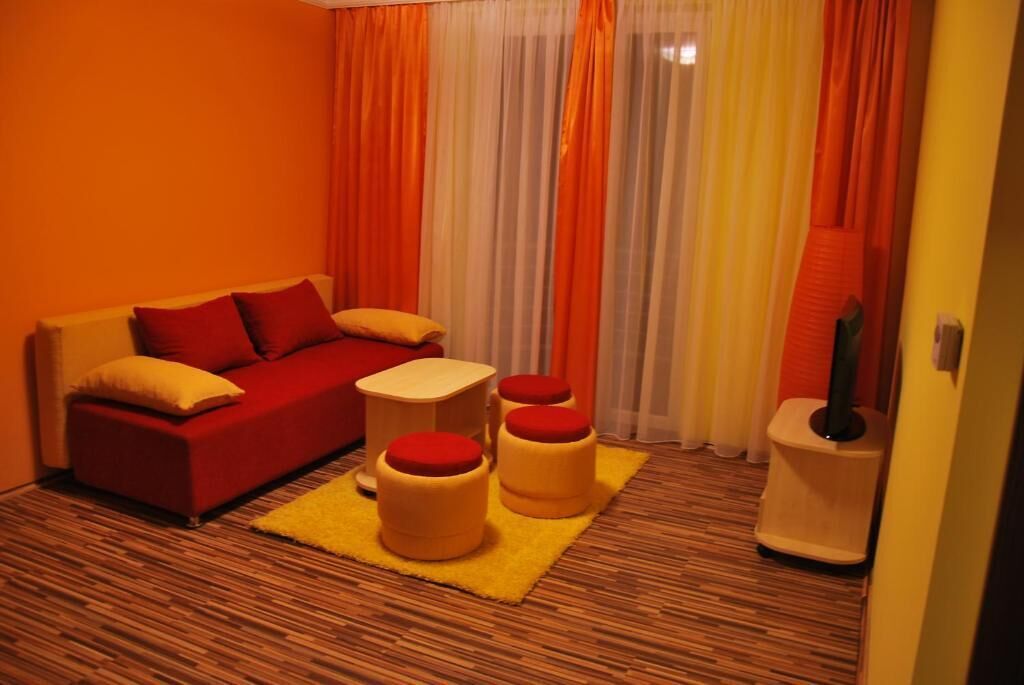A compact room with a red sofa, a small white table, and three yellow ottomans.