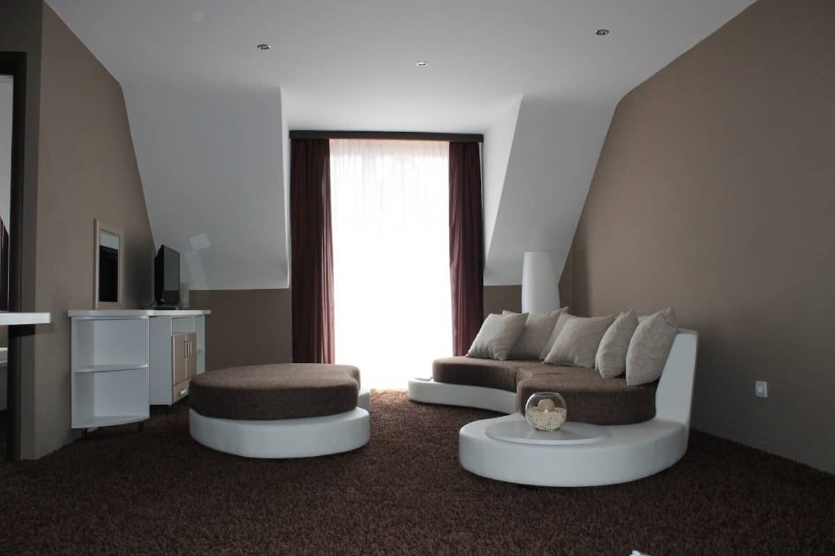 A modern, compact living space with a sofa, ottoman, and a small desk.