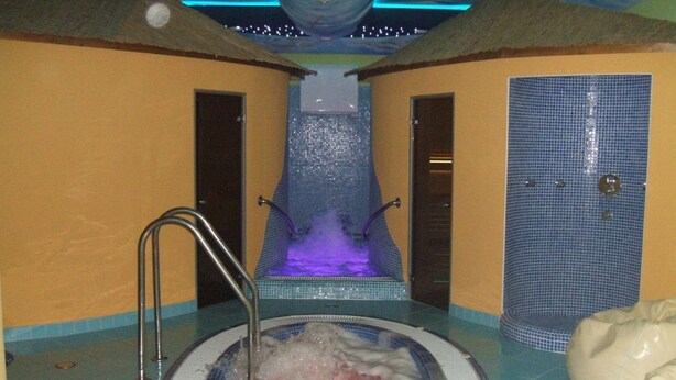 Un espacio de spa con un jacuzzi, ducha y pared de azulejos.