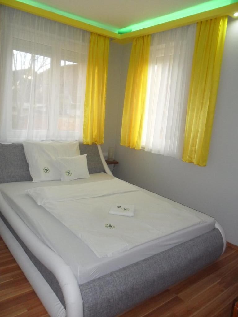 A bedroom with a bed, curtains, and a nightstand.