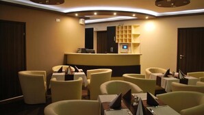 Un vestíbulo de hotel con una mesa de recepción, varias zonas de estar y un diseño de techo moderno.