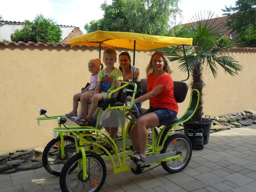 Una familia pasea en un triciclo verde con un toldo amarillo.