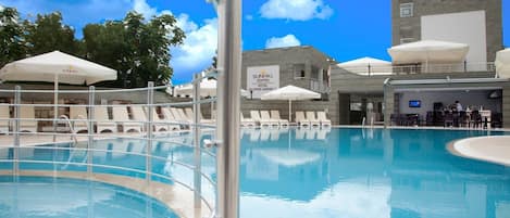 Una piscina al aire libre, sombrillas, sillones reclinables de piscina