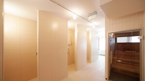 A modern hallway with white tiled walls and a wooden door leading to a sauna area.