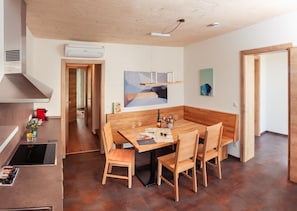 A modern kitchen with a dining area, wooden furniture, and a painting on the wall. - Ad Vineas Gästehaus Nikolaihof-hotel Garni (Mautern an der Donau)