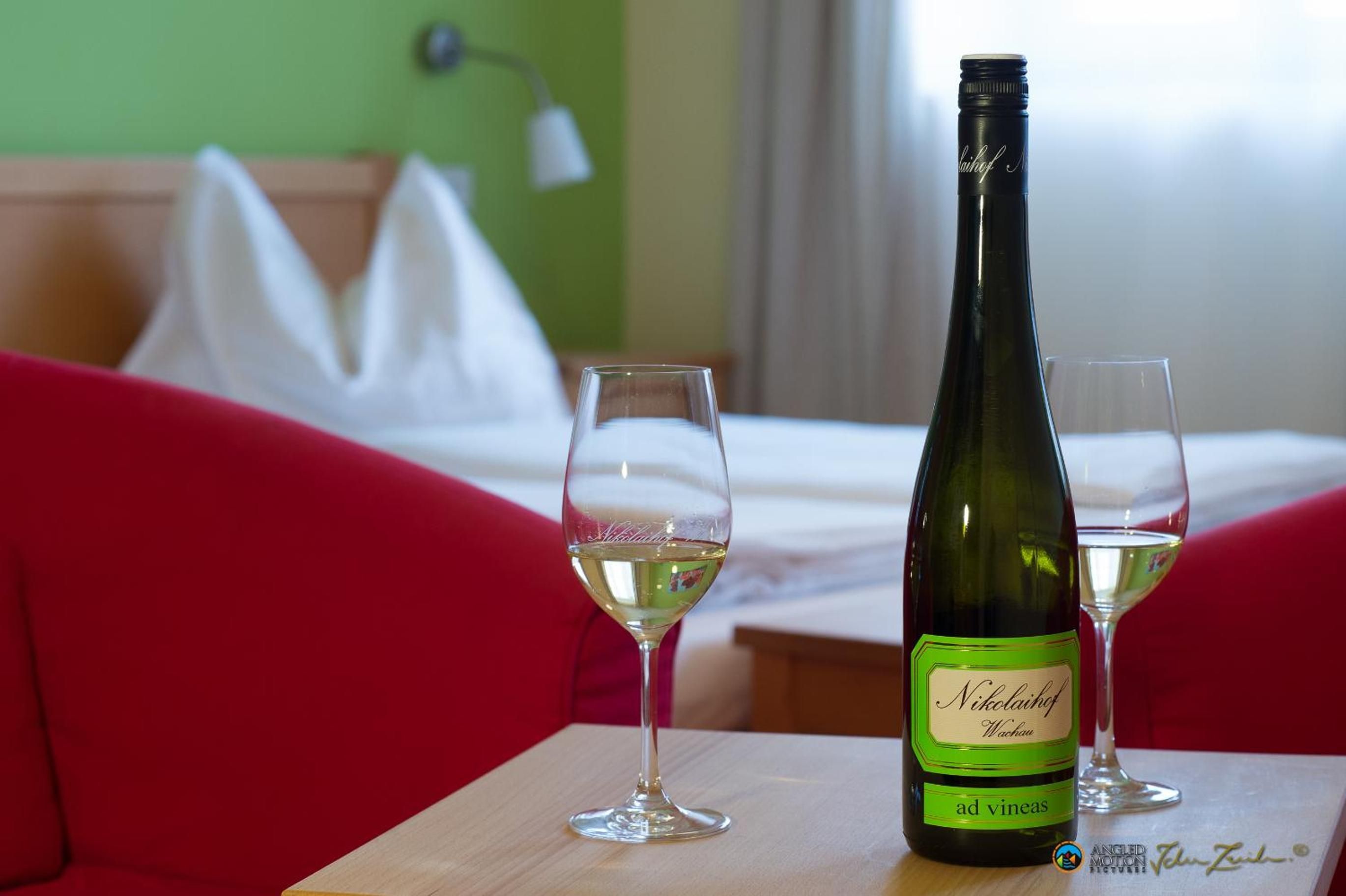 Una botella de vino y dos copas sobre una mesa de madera en una habitación de hotel.