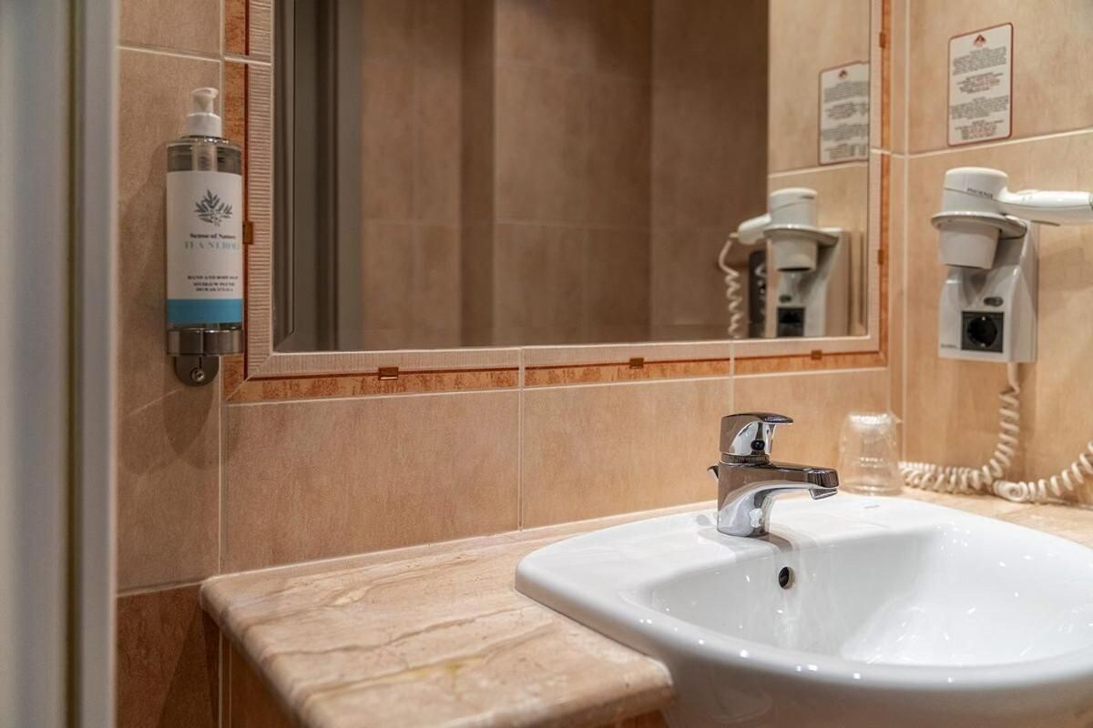 A bathroom with a sink, mirror, and a hand dryer.