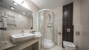 Un baño moderno con ducha de vidrio, lavamanos con encimera de mármol y retrete.