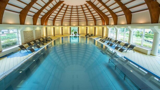 Una amplia piscina interior con techo abovedado y asientos a lo largo de los bordes.