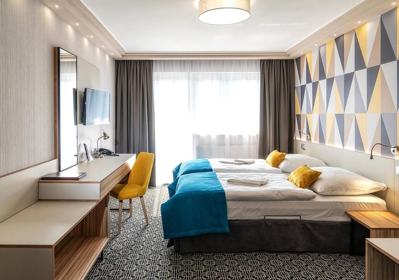 Habitación de hotel con cama, escritorio, silla, televisor y piso con diseño.