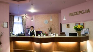 A reception desk with a clock, a framed certificate, and a flower vase. - Hotel Zawiercie (Zawiercie)