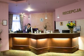 Un mostrador de recepción con un reloj, un certificado enmarcado y un florero.