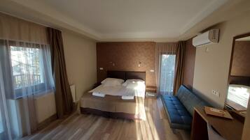 Habitación de hotel con una cama grande, una zona de estar y un escritorio con ordenador.