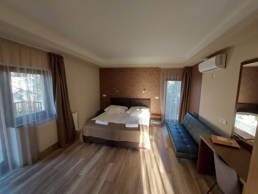 Habitación de hotel con una cama grande, una zona de estar y un escritorio con ordenador.