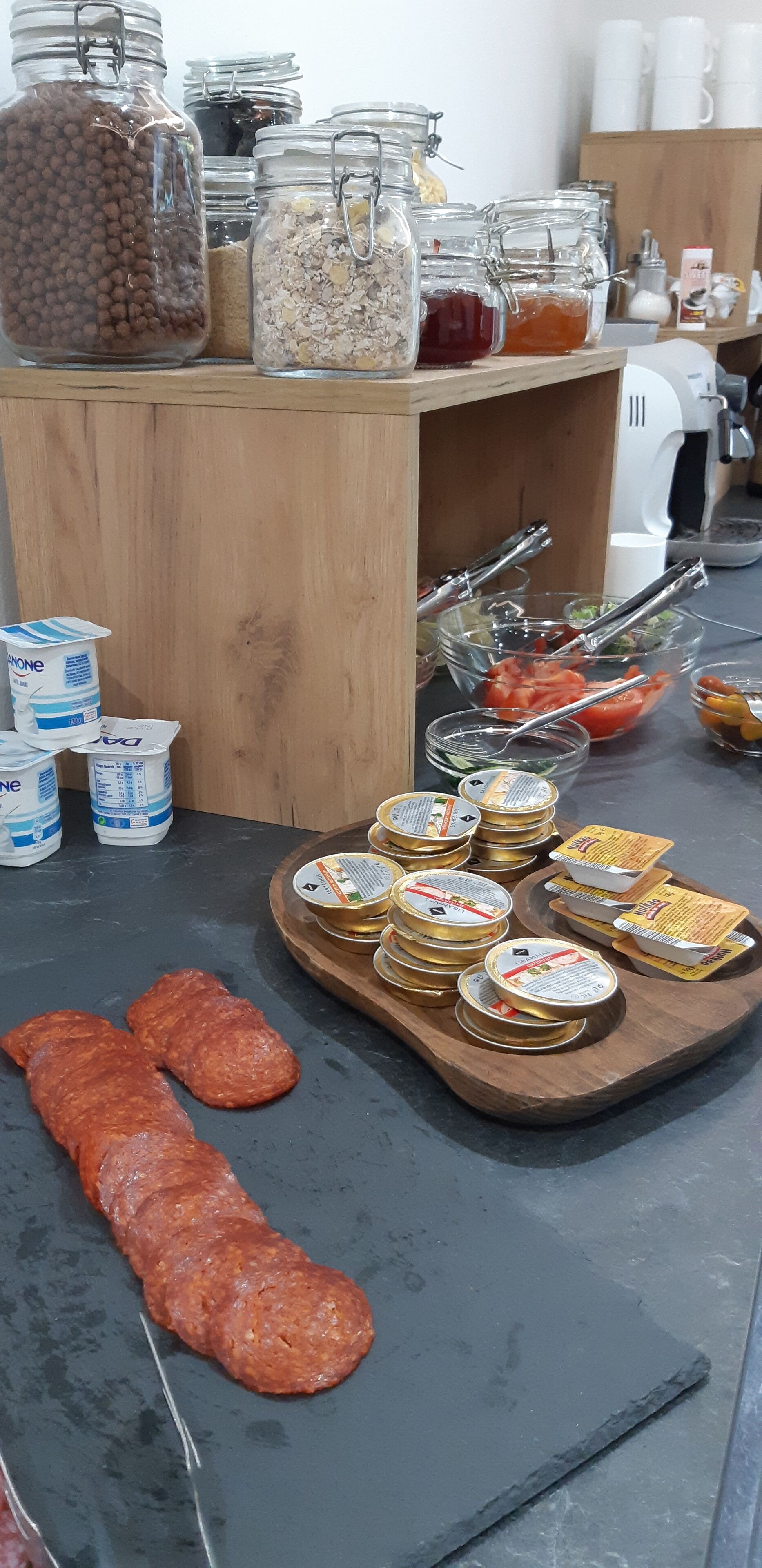 A kitchen counter with jars of food, a cutting board with meat, and various kitchen utensils.