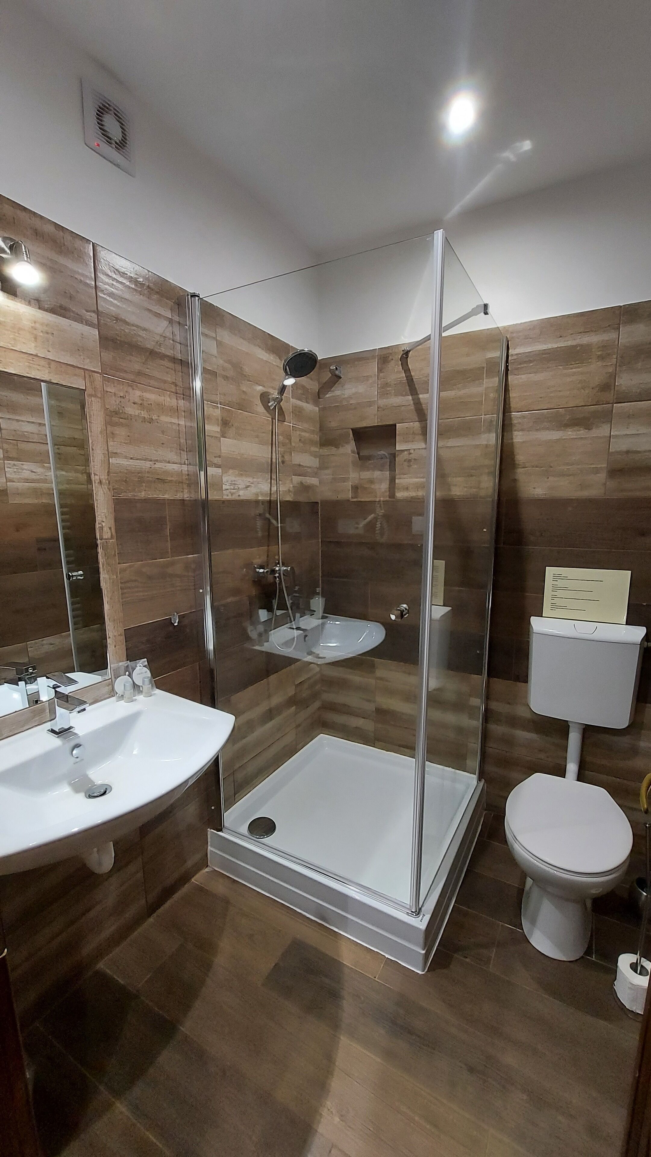 A modern bathroom with a glass-enclosed shower, a white sink, and a toilet.