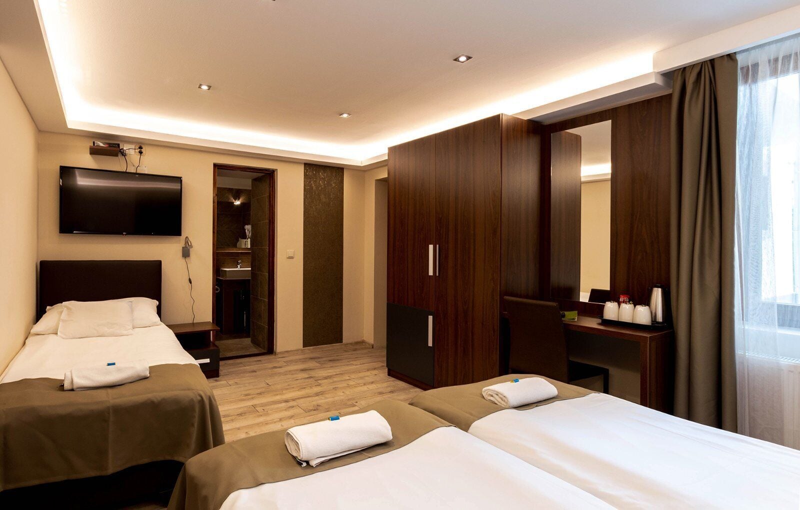 Habitación de hotel con dos camas, televisión, espejo, armario y baño.