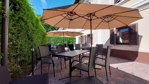 An outdoor patio with a table and chairs, surrounded by greenery and a building. - Vén Diófa De Lux Panzió (Szeged)