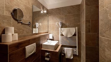 A modern bathroom with a wooden vanity, a sink, a mirror, and a towel rack.