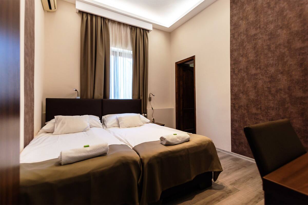 Habitación de hotel con dos camas, un escritorio y una silla.