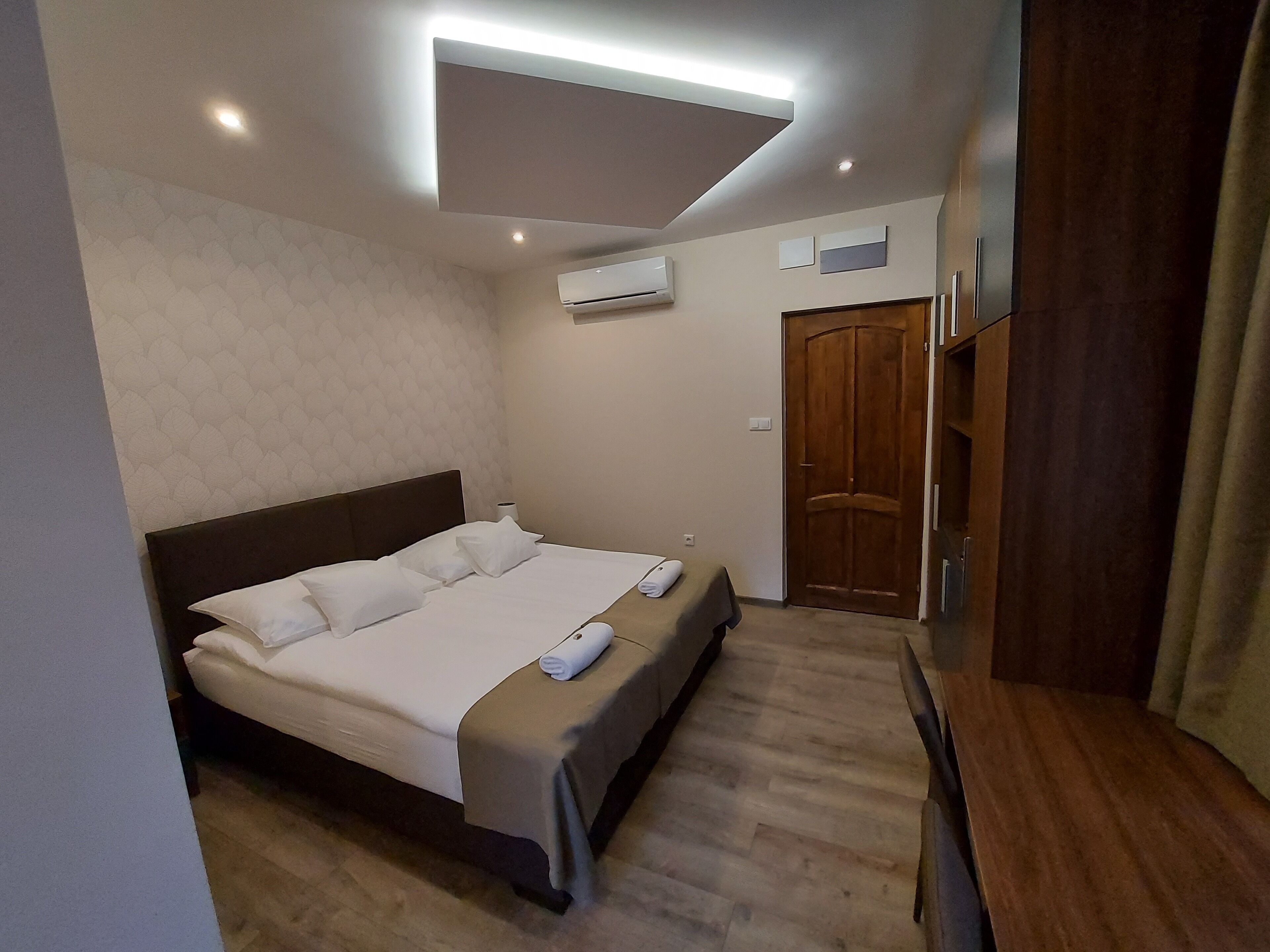 Habitació d'hotel amb llit, armari de fusta i aire condicionat.