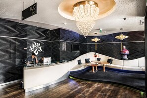A modern reception area with a curved desk, seating, and a chandelier.