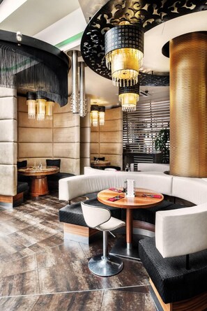 A modern interior with a round table, cushioned seating, and decorative lighting fixtures.