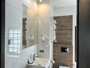 A modern bathroom with a large mirror, a sink, and a shower area.