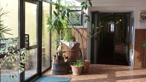 A hotel lobby with a large window, potted plants, and a wooden barrel.
