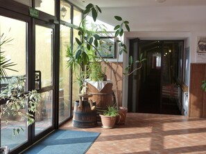 A hotel lobby with a large window, potted plants, and a wooden barrel.