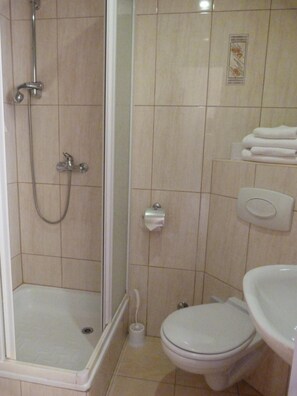 A bathroom with a shower, toilet, and sink.
