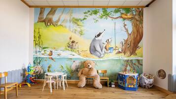 Children can play and explore in this vibrant playroom featuring a colorful mural and a variety of toys.