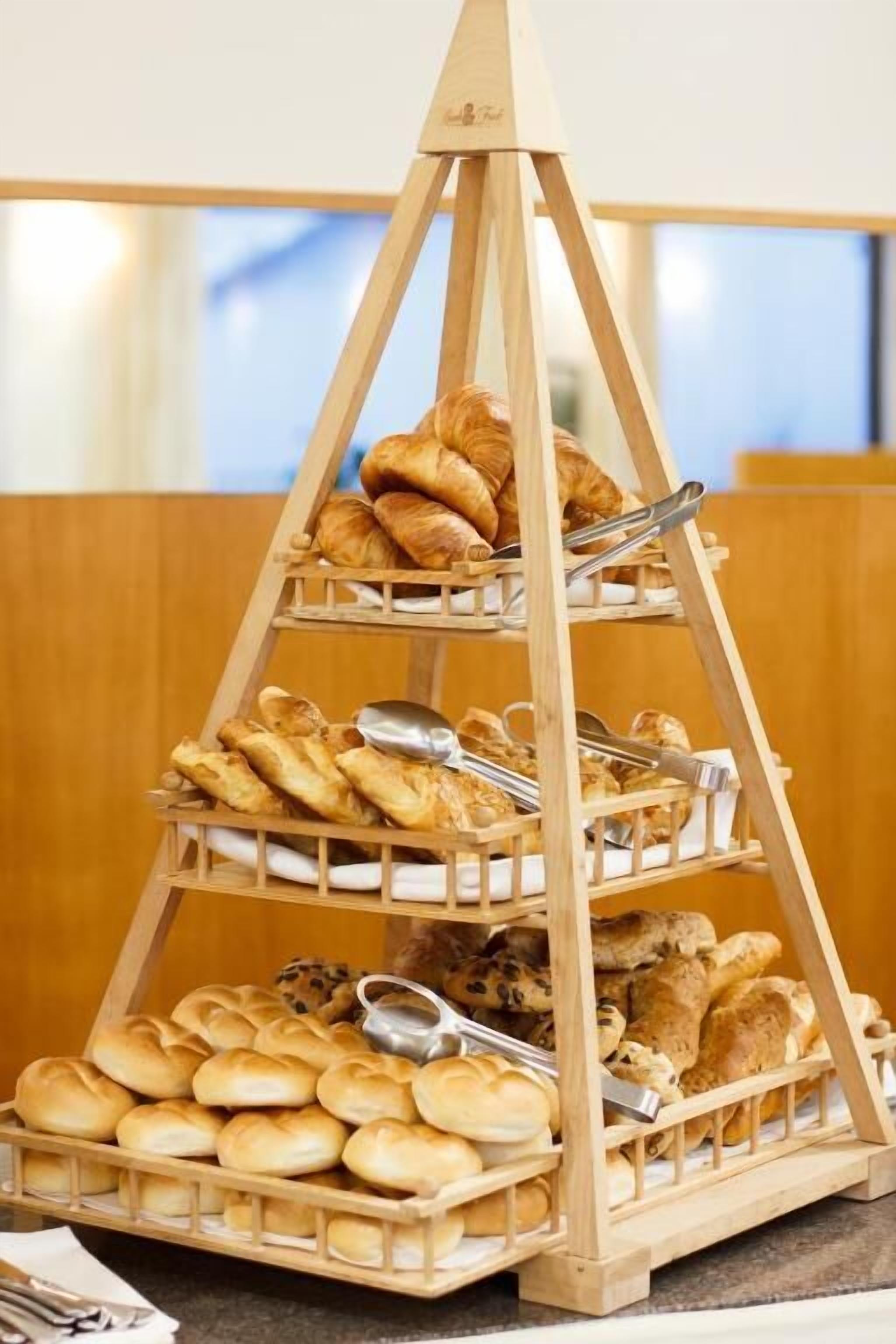 A wooden three-tiered display stand with various baked goods.