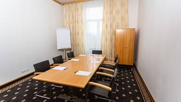 A conference room with a long table, chairs, a whiteboard, and a wardrobe.