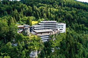 Un hotel de varios pisos llamado "SPORTHOTEL" ubicado en zona boscosa, con una localización en un acantilado.