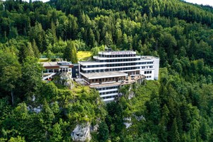 Um hotel com vários andares chamado "SPORTHOTEL", situado numa área arborizada com localização à beira de um penhasco.
