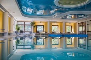Piscina interna com reflexos nítidos, paredes amarelas e grandes janelas.