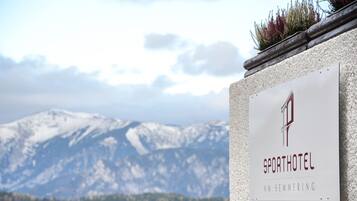 Schild des Sporthotel Am Semmering, im Hintergrund eine Bergblick.