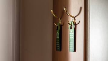 A wooden door with two green tags hanging on a brass hook.