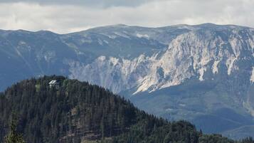 A mountain cabin surrounded by dense forest and rugged mountains.