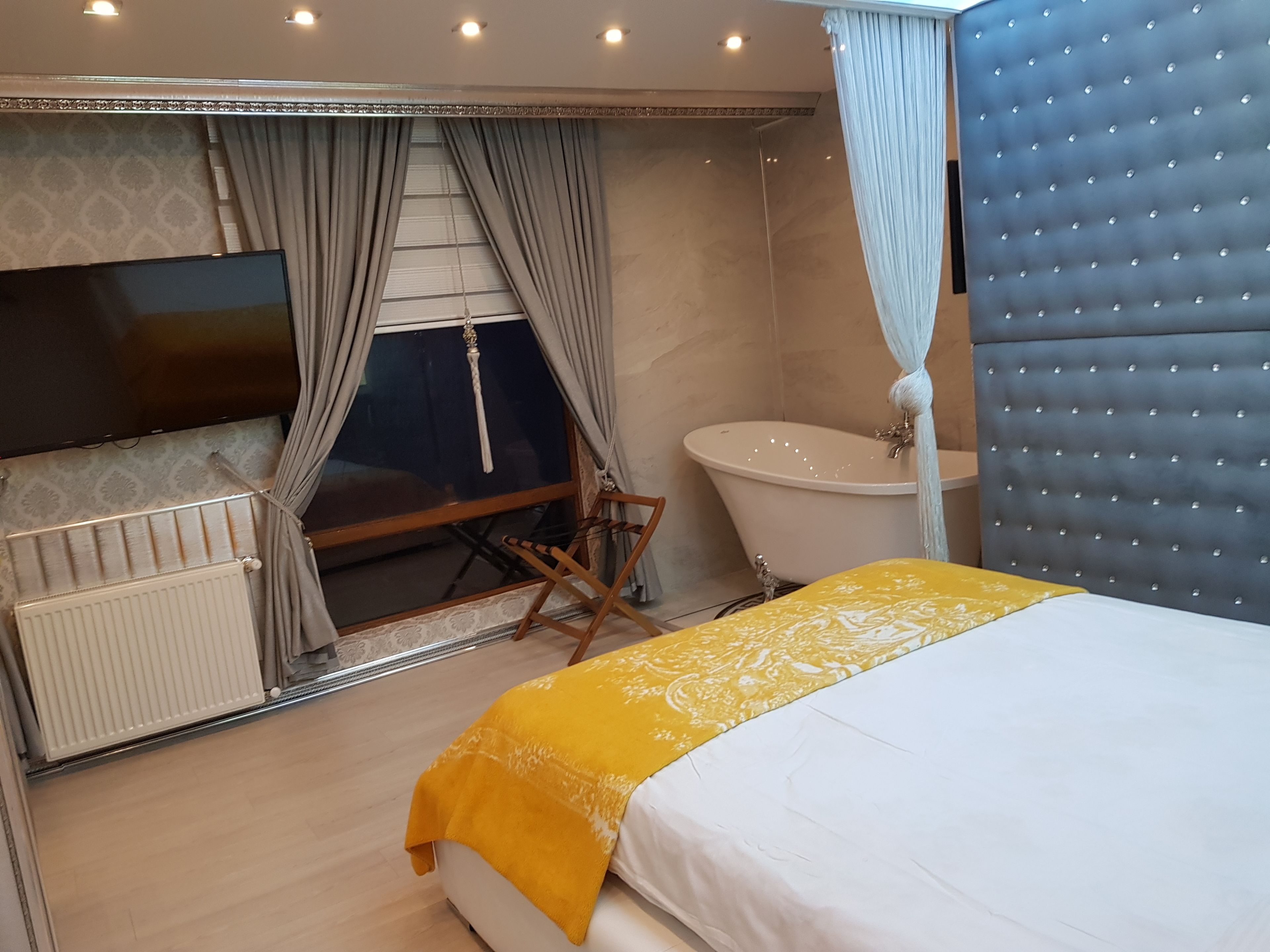 Une chambre à coucher avec un lit, une baignoire et une fenêtre avec des rideaux.