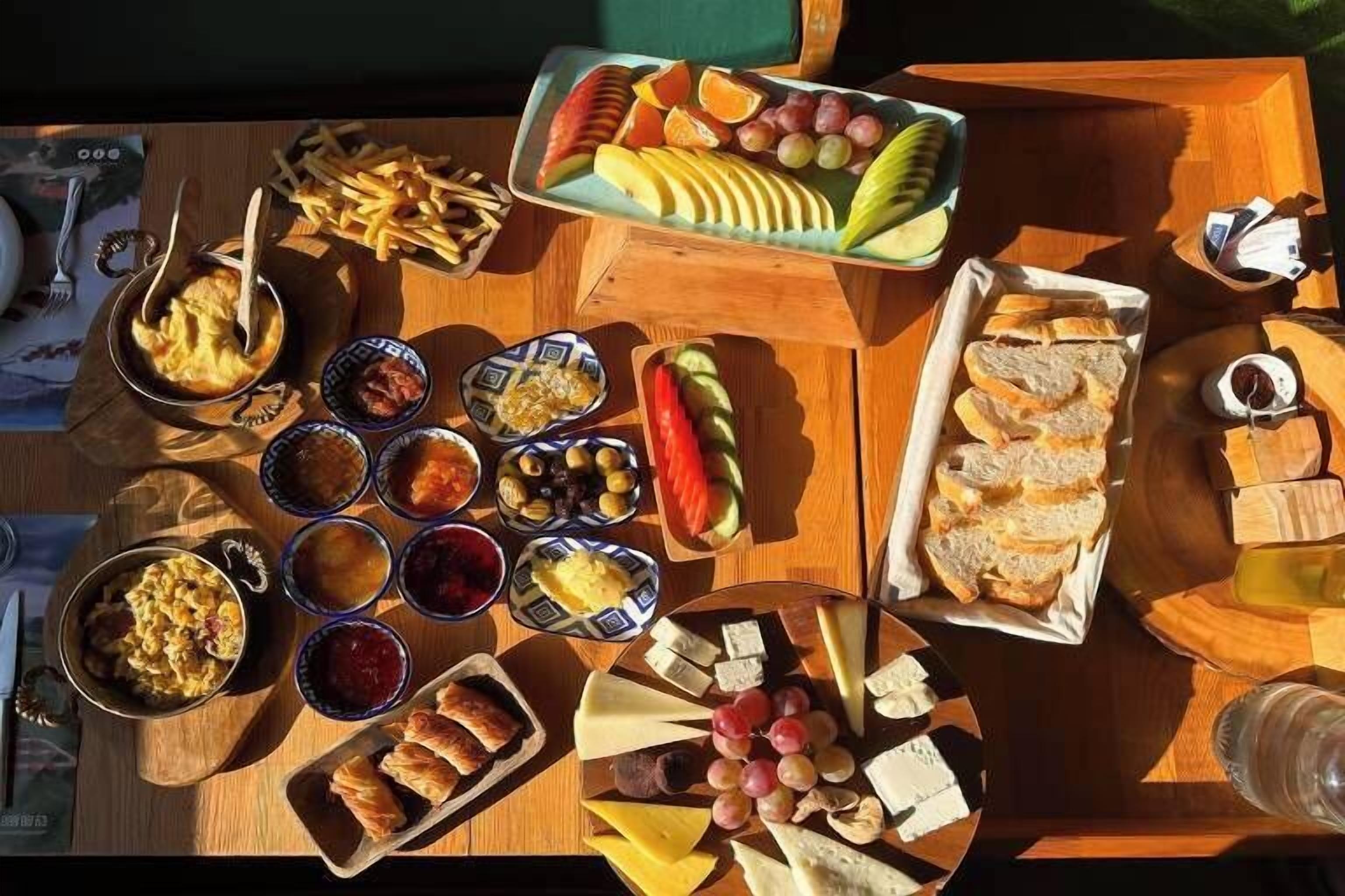 A wooden table with various food items including fruits, cheeses, and bread.
