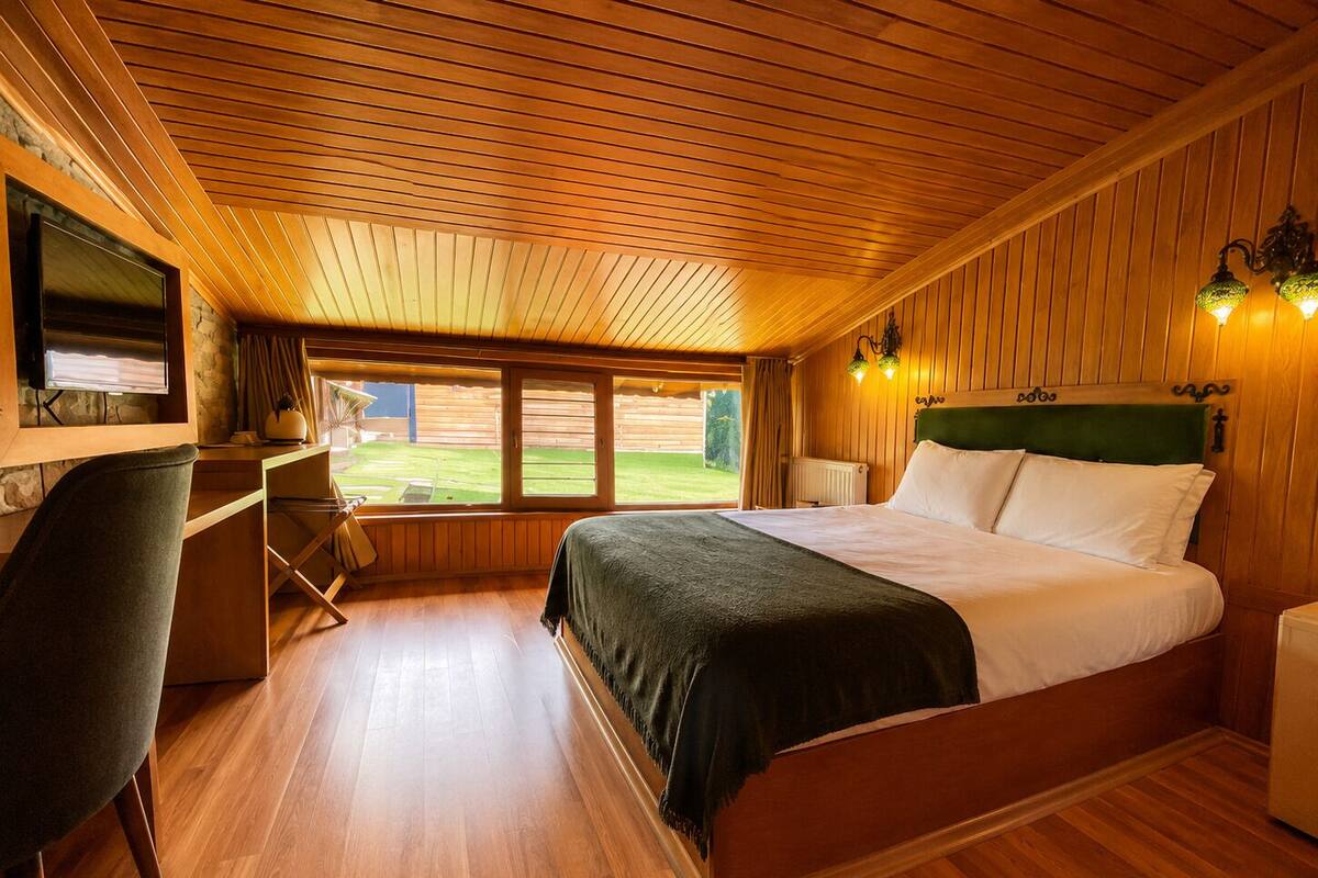 A bedroom with a bed, a desk, a chair, and a television.