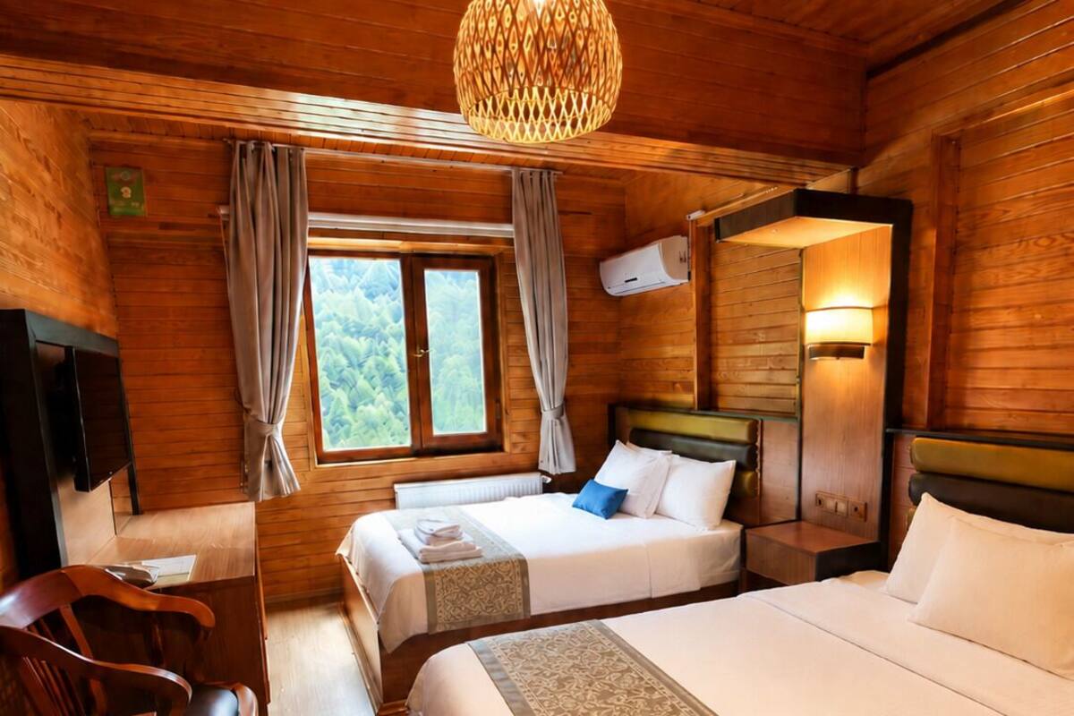 A wooden cabin-style room with two beds, a desk, and a chair.