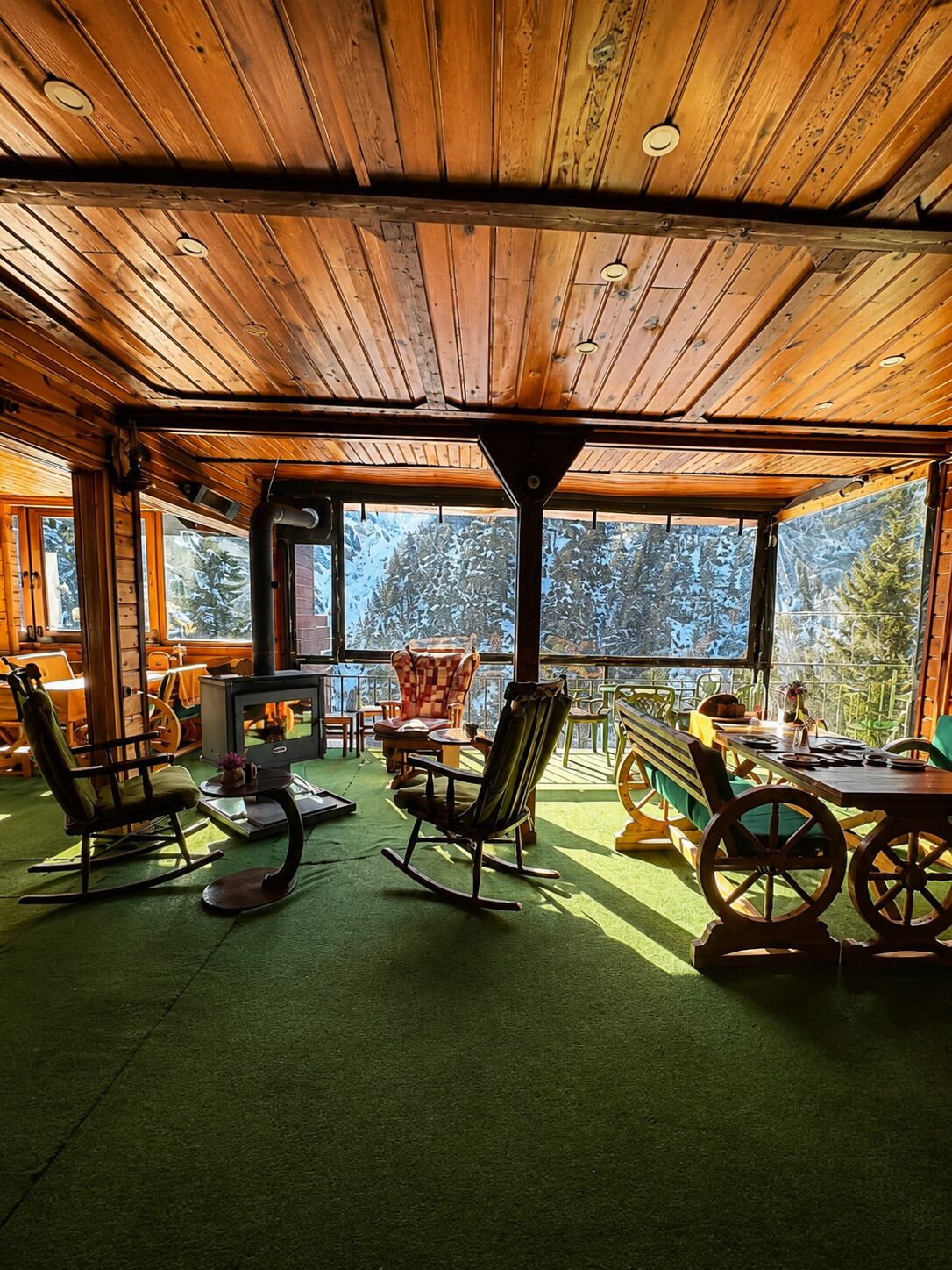 Interior acogedor de una cabaña con chimenea, sillones mecedores y comedor.