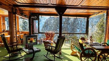 Interior acogedor de una cabaña con chimenea, sillones mecedores y comedor.